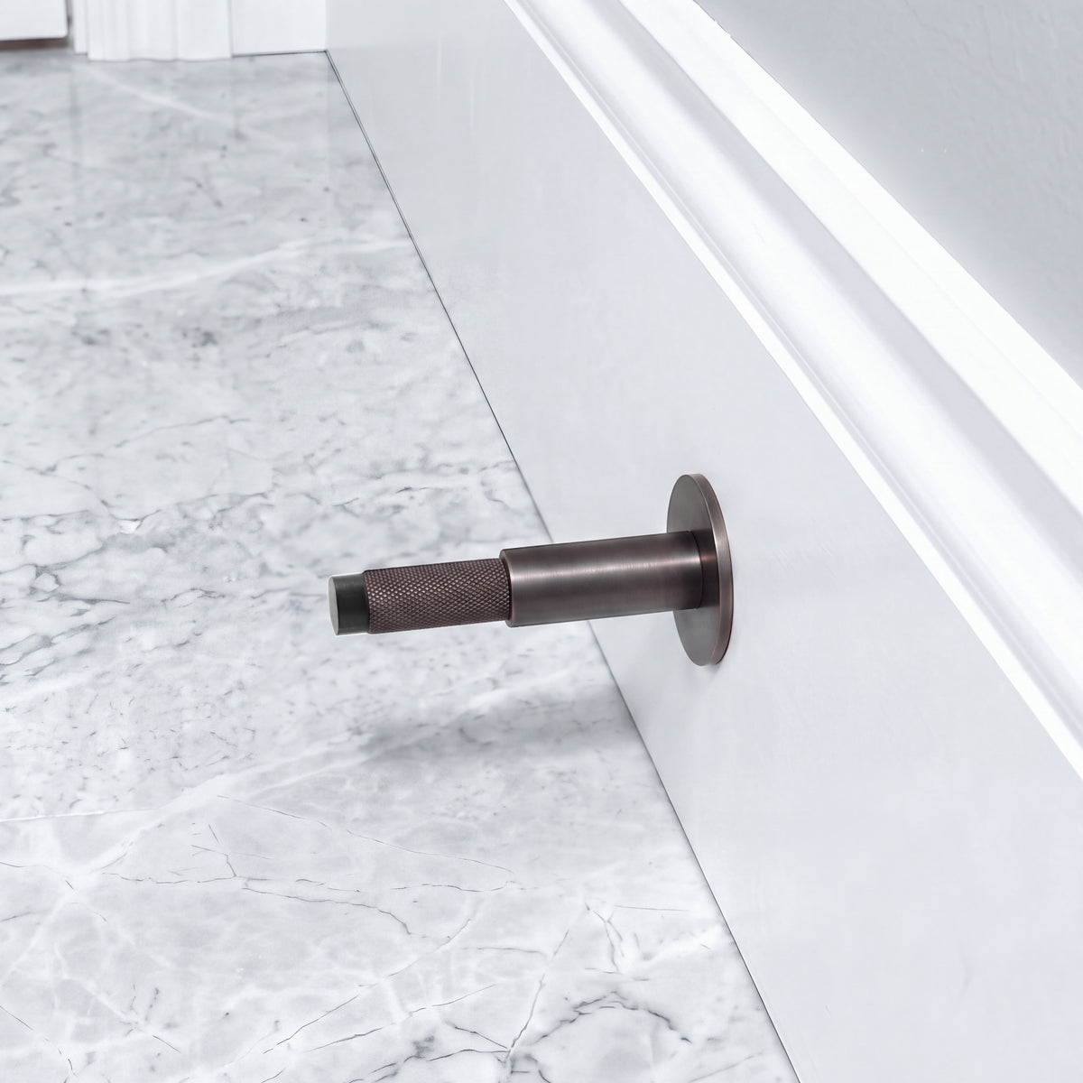 Halo Door Stop in Antique Copper Brass installed on a marble floor