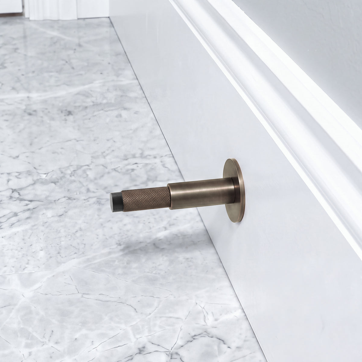 Halo Door Stop in Antique Brushed Bronze installed on a marble floor